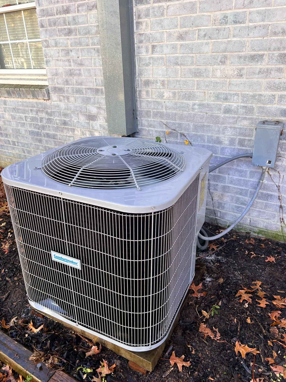 Condenser service beside a brick home