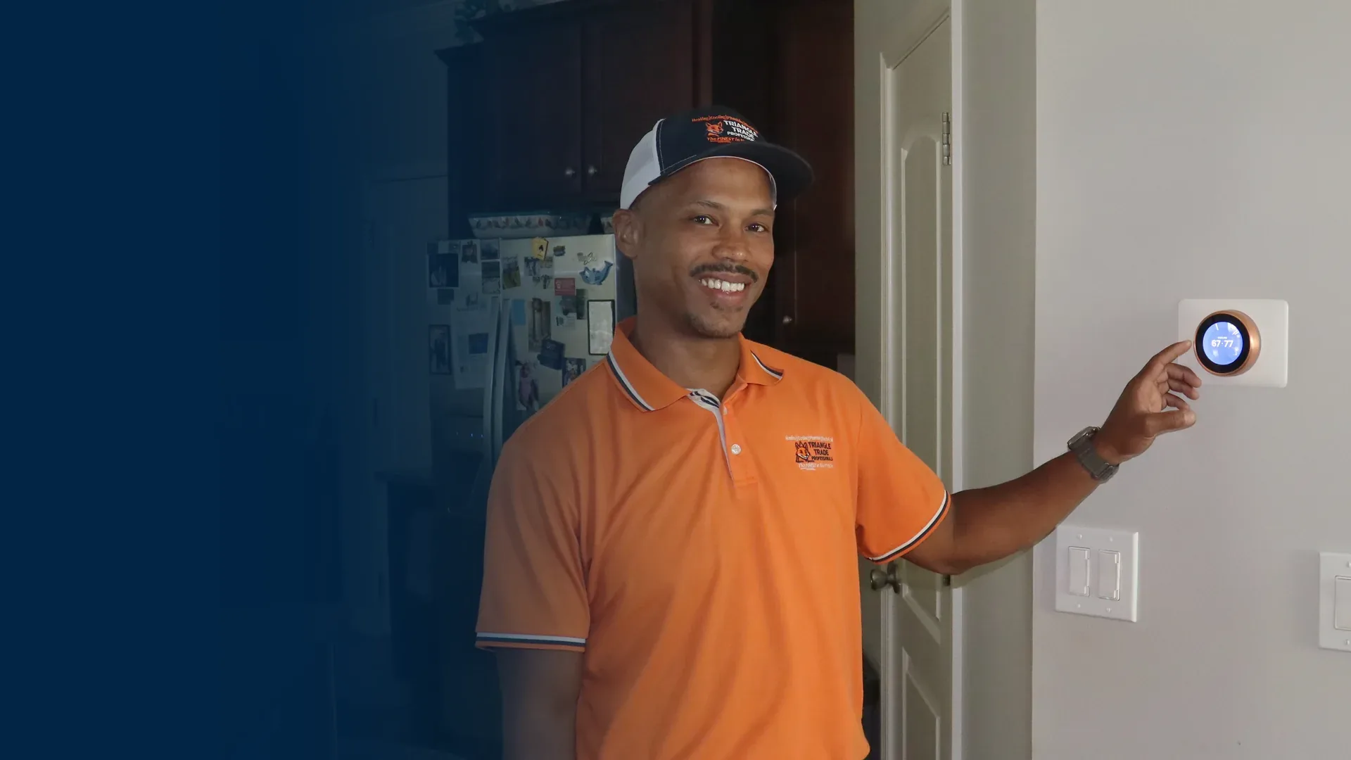 Joel Verley, owner of Triangle Trade Professionals, smiling with his hand on a smart thermostat in a customer's home